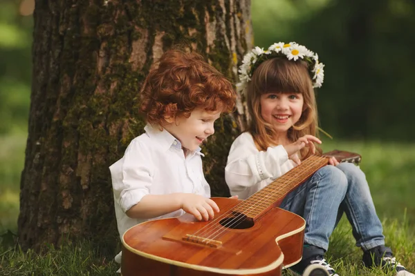Niño y niña tocando la guitarra en el parque de verano —  Fotos de Stock
