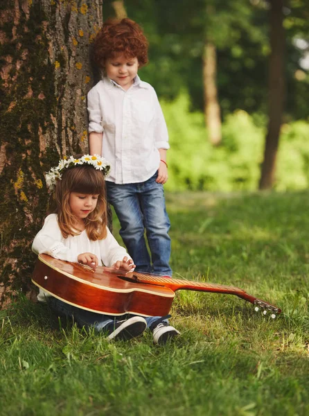 Boy and girl playing guitar in summer park — Stock Photo, Image