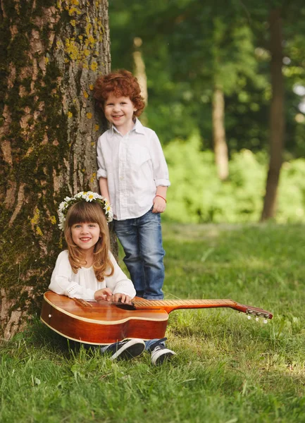 Junge und Mädchen spielen Gitarre im Sommerpark — Stockfoto