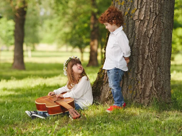 Garçon et fille jouer de la guitare dans le parc d'été — Photo