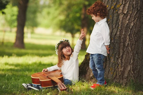 Niño y niña tocando la guitarra en el parque de verano — Foto de Stock