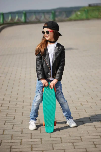 Маленькая девочка со скейтбордом на улице — стоковое фото