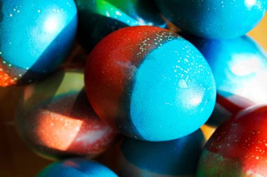 Paskalya için canlı renkli yumurtalar kırmızı ve mavi kağıtların üzerinde duruyor.