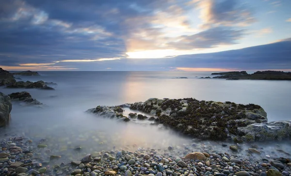 Early morning landscape of ocean over rocky shore with glowing s — Stock Photo, Image