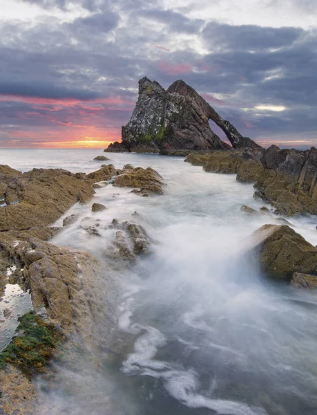 Sunrise with red clouds at bow fiddle rock near Portknockie — Stock Photo, Image