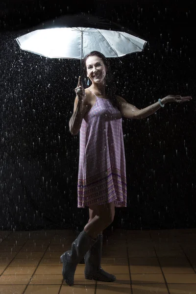 Piękna kobieta z różowa sukienka pod parasolem w nocy — Zdjęcie stockowe