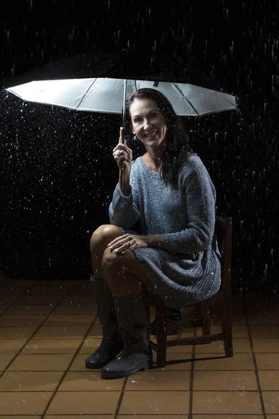 Hermosa mujer con vestido de plata sentado bajo un paraguas en n — Foto de Stock