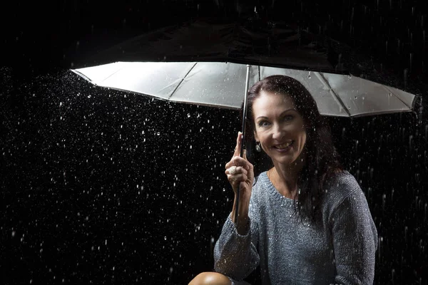 Mulher bonita com vestido de prata sentado sob um guarda-chuva em n — Fotografia de Stock