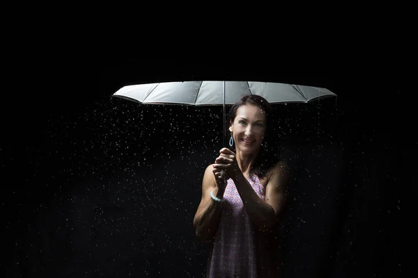 Mulher bonita com vestido rosa sob um guarda-chuva à noite — Fotografia de Stock