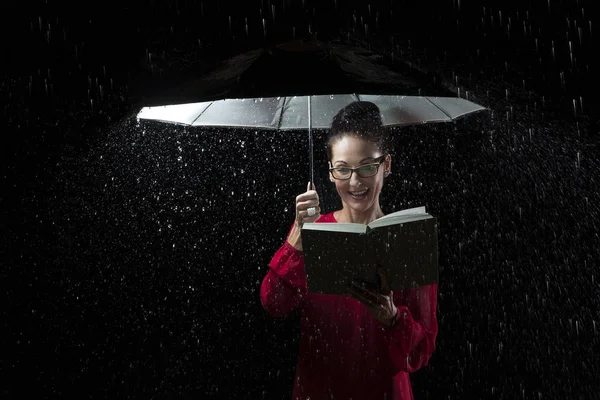 Женщина в красном платье читает книгу под дождем — стоковое фото