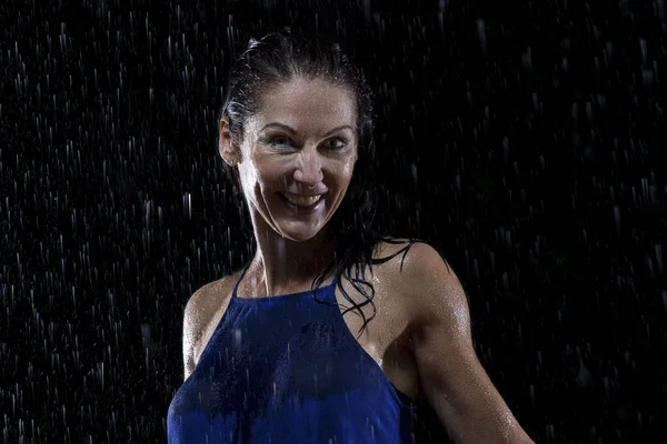 Mooie vrouw in blauwe jurk staat in de regen 's nachts — Stockfoto