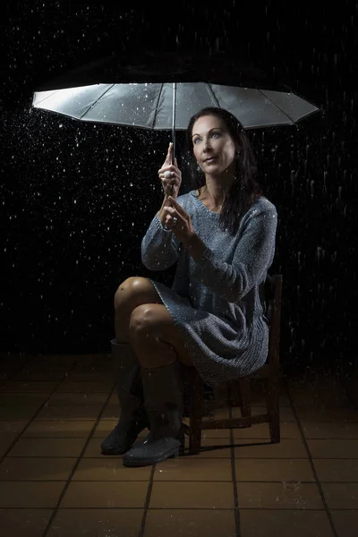 Mulher bonita com vestido de prata sentado sob um guarda-chuva em n — Fotografia de Stock