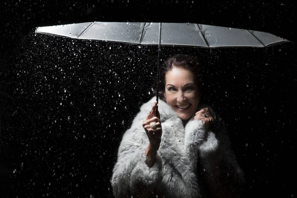 Bella donna con pelliccia in piedi sotto la pioggia sotto un ombrello — Foto Stock