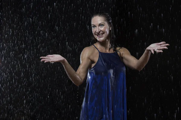 Piękna kobieta w niebieskiej sukience stoi w deszczu w nocy — Zdjęcie stockowe