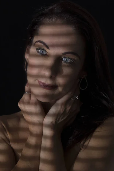 Portrait of a woman standing in darkness with shadow lines of bl — Stock Photo, Image