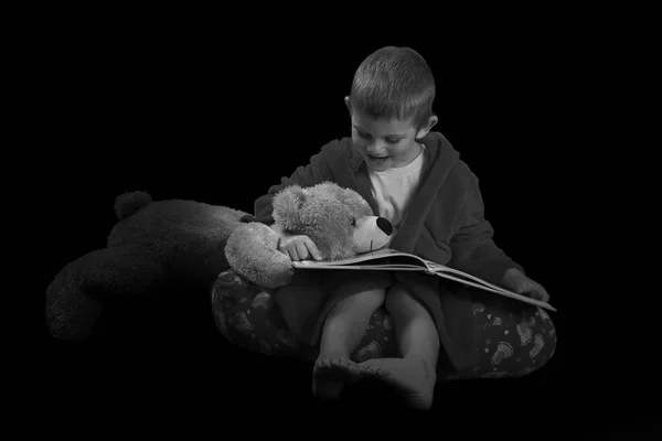 Funny boy with a teddy bear reading a book for bed time in artis — Stock Photo, Image