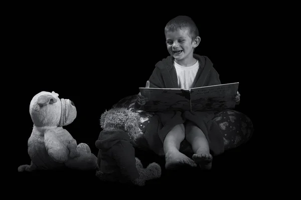 Chico gracioso con un osito de peluche leyendo un libro para dormir en artis — Foto de Stock