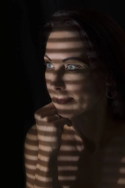 Ritratto di una donna in piedi nell'oscurità con linee d'ombra di bl — Foto Stock