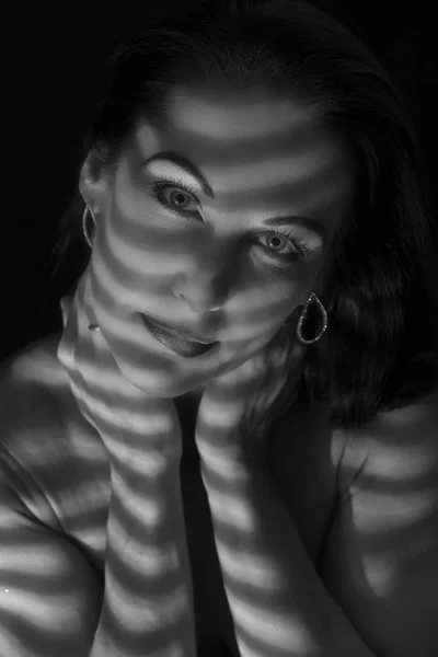 Portrait of a woman standing in darkness with shadow lines of bl — Stock Photo, Image