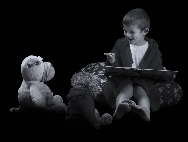 Divertente ragazzo con animali di peluche che leggono un libro prima di andare a letto ar — Foto Stock