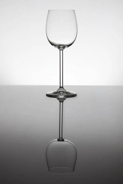 Empty wine glasses standing on a reflective surface with perfect — Stock Photo, Image