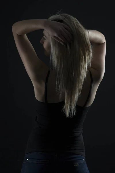 Beautiful blond woman in denim and black top in the dark with se — Stock Photo, Image