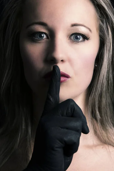 Frightened blonde woman silenced with finger in black on her fac — Stock Photo, Image