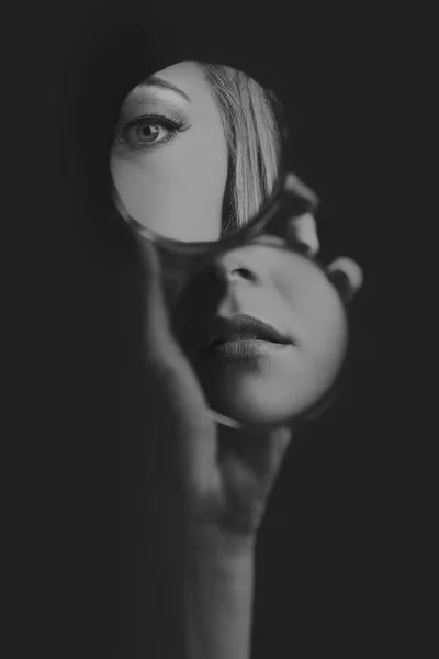 Frau blickt in kleinem Spiegel auf Augen und Mund — Stockfoto