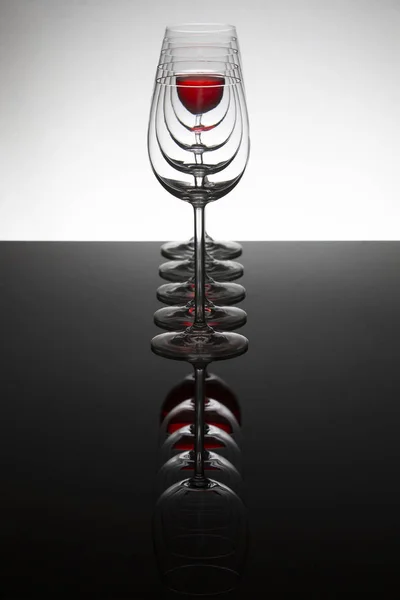 Row of empty wine glassesand one filled at the rear distort the — Stock Photo, Image