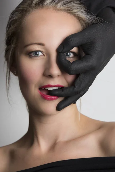 Piękna Blondynka kobieta patrząc przez palce o black hand — Zdjęcie stockowe