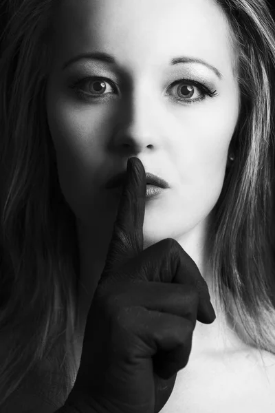 Mujer rubia aterrorizada silenciada con el dedo en negro en su fac —  Fotos de Stock