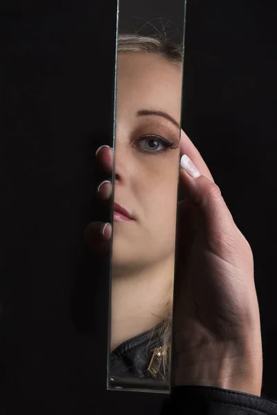 Woman looking at her face in shard of broken mirror — Stock Photo, Image