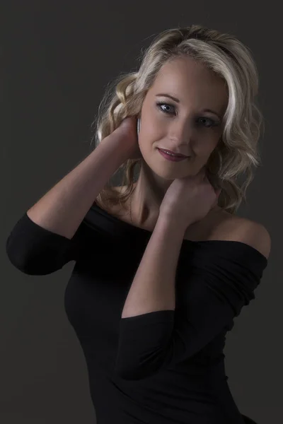Красива блондинка в чорному зверху в темряві з вибірковим світлом — стокове фото