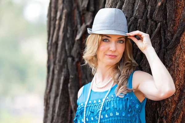 Retrato de una mujer rubia con un vestido azul y sombrero al aire libre — Foto de Stock