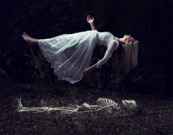 Левитационное изображение женщины, восходящей из скелета на некоторых мертвых листьях
