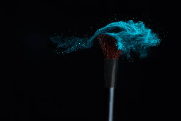 黒の背景に青い粉体爆発でメイクブラシ — ストック写真
