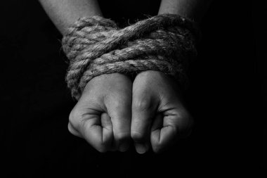 Conceptual monochrome image of woman hands tied with a coarse rope and selective lighting clipart