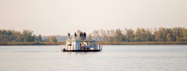 Petropavlovsk, Kazakistan - 14 Eylül 2019: nehirde beyaz zevk gemisi. Geminin güvertesinde insanlar var. Nehir ve ağaçların sonbahar manzarası.