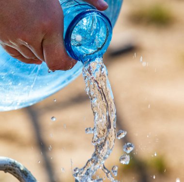 Teneke kutudan yemek pişirmek için su dökülür..