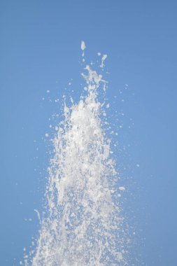 Mavi gökyüzüne karşı Su Çeşmesi sprey. Su sıçramaları odak dışında.