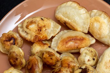 Bir tabakta kızarmış ravioli, kızarmış börek yemek.