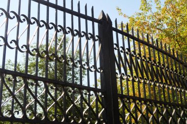 Bir kır parkının bahçesi boyunca metalik dekoratif bir çit..