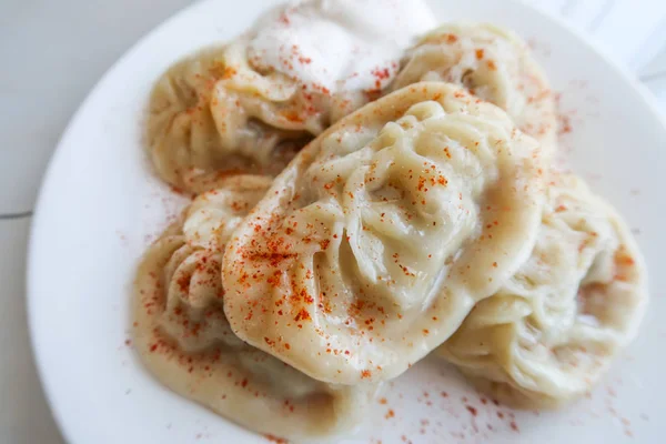 Manty dough with the filling is steamed. Food on a white torch.