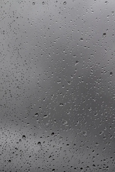 玻璃上的雨滴 阴沉的天气灰色背景 雨灰云玻璃纹理 图库照片