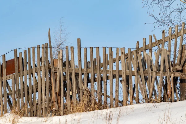 冬には屋外の木製の古いフェンス 冬の雪の中で素朴な木製フェンスのポスト砂漠の植物で覆われたシーン — ストック写真