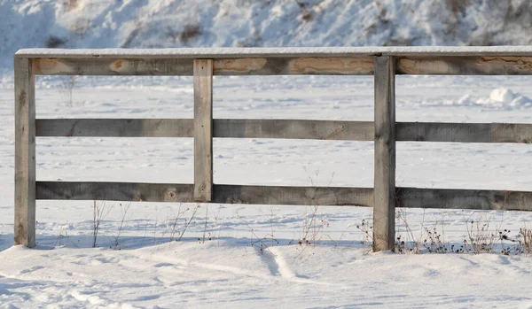 Wooden old fence outdoors in winter. Rustic wooden fence post in winter snow covered scene with desert plants.