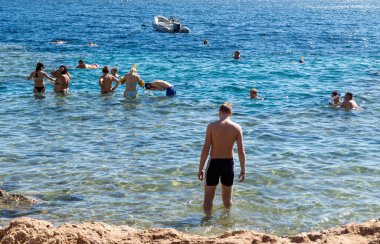 Sharm El Sheikh, Mısır - 1 Şubat 2020: Deniz kenarında yoğun bir yaz tatili. Güneşli bir günde insanlar denizde ve sahilde, güneşleniyorlar, yüzüyorlar.