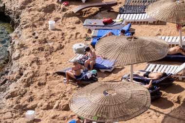 Sharm El Sheikh, Mısır - 1 Şubat 2020. Deniz kenarındaki plaj salonları, şemsiyeler, insanlar dinleniyor. Deniz kenarında yoğun bir yaz tatili. Güneşli bir gün, güneş banyosu, yüzme.
