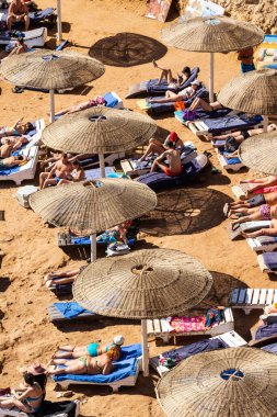 Sharm El Sheikh, Mısır - 1 Şubat 2020. Deniz kenarındaki plaj salonları, şemsiyeler, insanlar dinleniyor. Deniz kenarında yoğun bir yaz tatili. Güneşli bir gün, güneş banyosu, yüzme.