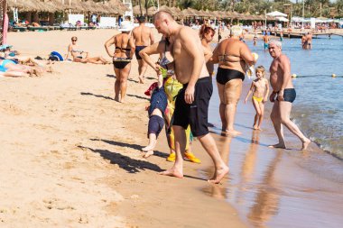 Sharm El Sheikh, Mısır - 1 Şubat 2020: Deniz kenarında yoğun bir yaz tatili. Güneşli bir günde insanlar denizde ve sahilde, güneşleniyorlar, yüzüyorlar.